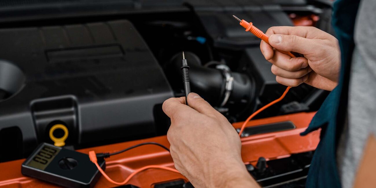 cropped shot of auto mechanic with multimeter volt 75JAMKL