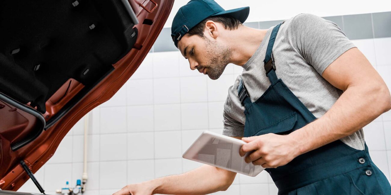 side view of auto mechanic with tablet checking ca CJFYZUR
